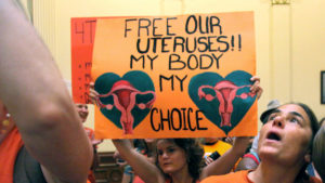 Pro-choice protester holds a sign saying "free our uteruses! My body my choice."
